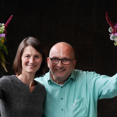 Miriam Staudte und Detlev Schulz-Hendel lächeln und schwenken Blumensträuße