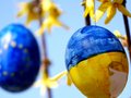 Beschädigtes Osterei in ukrainischen Nationalfarben vor Osterei in EU Farben