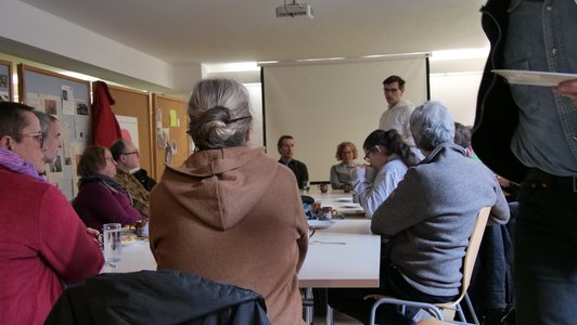 Blick über einige der Besucher*innen und den Tisch, an dem sie sitzen